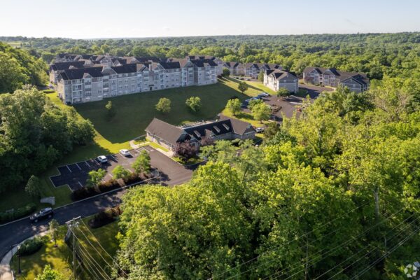 Aerial view of the Waters Bend apartment complex showing multiple buildings, green spaces, parking areas, and surrounding wooded landscape.